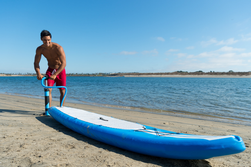 A guy pumping up a inflatable stand up paddle board